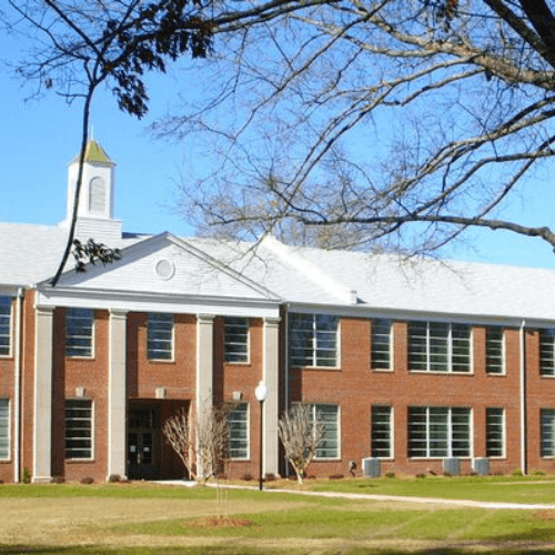 A large red brick building with a white tower and a clock on the front.